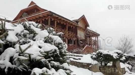 大雪时山村的木屋，背景是针叶林。落在原木上的雪视频