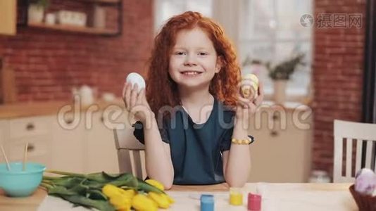 欢快的红头小女孩在厨房背景上玩复活节彩蛋的肖像。 她在欢呼视频