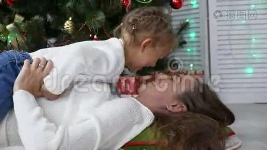 可爱的小女孩玩得开心，在圣诞树旁边亲吻她的妈妈视频