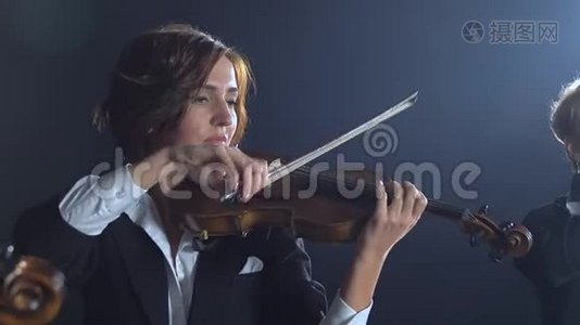 女孩们在房间里演奏小提琴。 黑烟背景视频