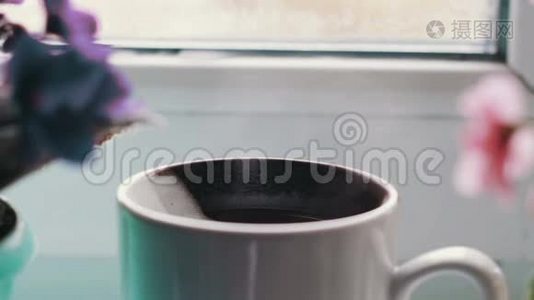 一杯热饮料，蒸汽，站在窗台上，四周开花，近景视频