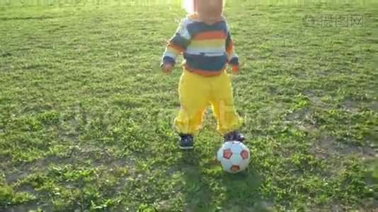 一个半岁的男孩高兴地在球场上追逐球视频
