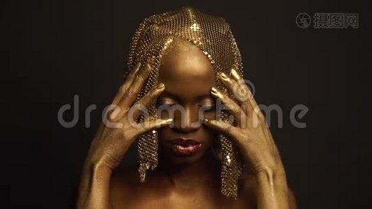 神秘的非洲裔美国女性模特，金色光泽的化妆和头饰，为相机。 高级时尚时尚时尚视频