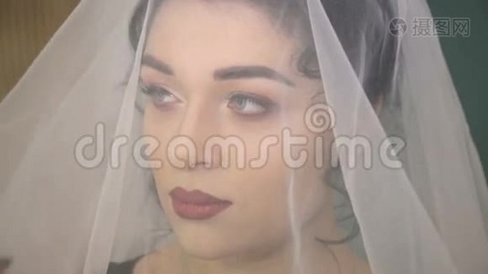 年轻美丽的新娘在白色婚纱下的脸视频