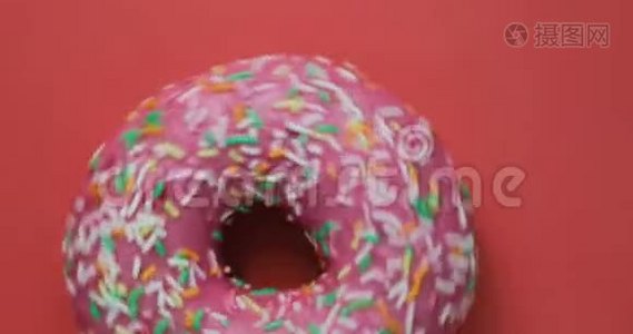 明亮而多彩的甜甜圈特写镜头旋转在红色背景上。 美味的甜甜甜面圈视频
