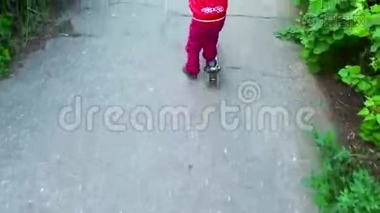 女孩骑着滑板车在沥青路上。视频