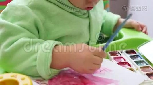 一个快乐的孩子用画笔在纸上画画视频