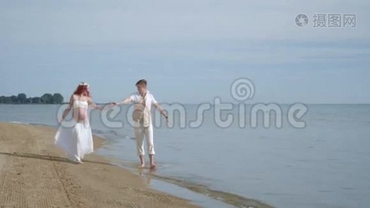 一对散步海滩。 在海边怀孕的夫妇。 海滩上的孕妇视频