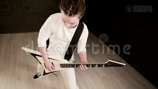 时尚的独奏吉他手，头上戴着可怕的石头，黑色背景上穿着白色衣服，富有表现力地演奏着视频