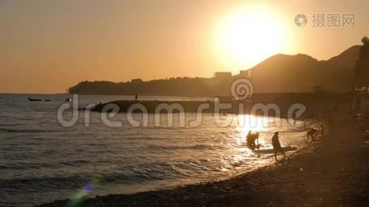 夕阳西下的海山，沙滩上的太阳落山，人们在沙滩上。视频