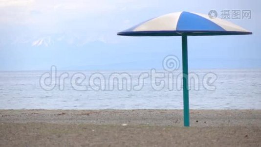 空的沙滩和蓝色的太阳伞迎着雪峰.. 4K低季视频视频