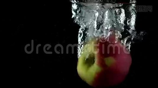 在黑色背景下，苹果掉进水里。 超级慢动作视频