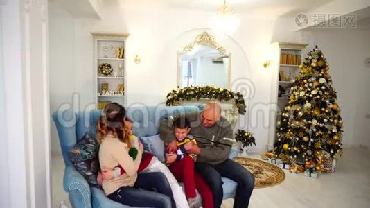欢乐、欢乐、欢乐的家庭在节日装饰的房间里坐在蓝色的沙发上视频