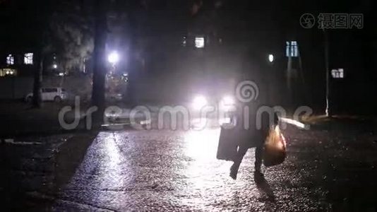 女人带着一个手提箱和一个袋子穿过黑暗的院子视频