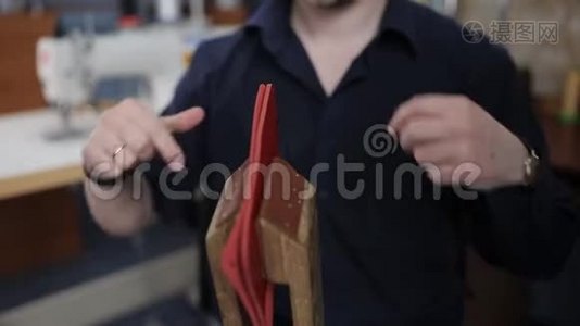男人用自己的手在皮革车间里用一根针制造一个棕色的皮夹视频