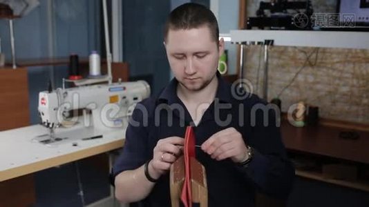 男人用自己的手在皮革车间里用一根针制造一个棕色的皮夹视频