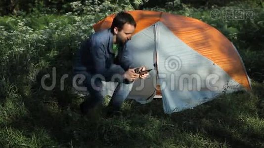 在森林里的帐篷旁边的一块平板电脑上有人拍照视频