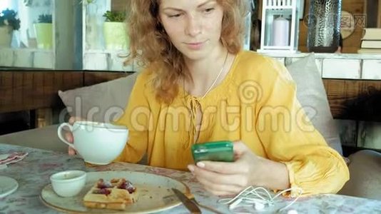美女正在咖啡馆吃华夫饼，用智能手机拍照视频