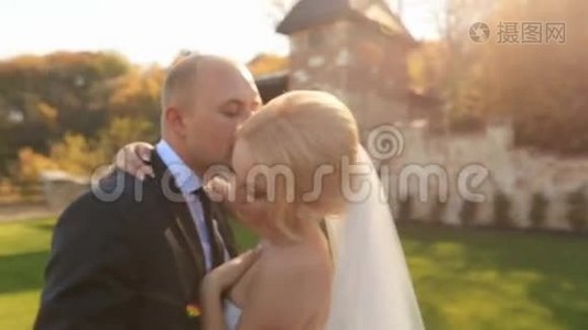 新婚快乐的新婚夫妇在中世纪城堡的院子里轻轻地接吻视频