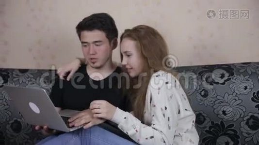 家庭，技术和关系概念-英俊的夫妇与笔记本电脑在家。视频