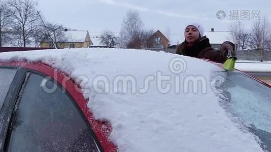 女孩在红色汽车的屋顶上擦雪。 冬季缓慢运动.视频