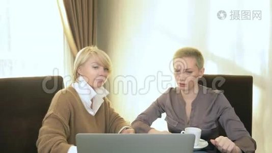 两个女人坐在笔记本电脑前的办公室里说话视频