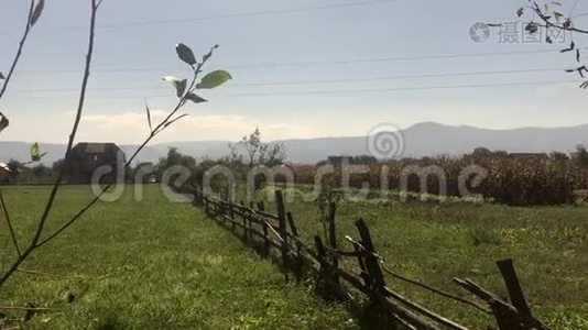 一座山谷的风景。 远处是小山，靠近农田和一座古老的木栅栏。视频