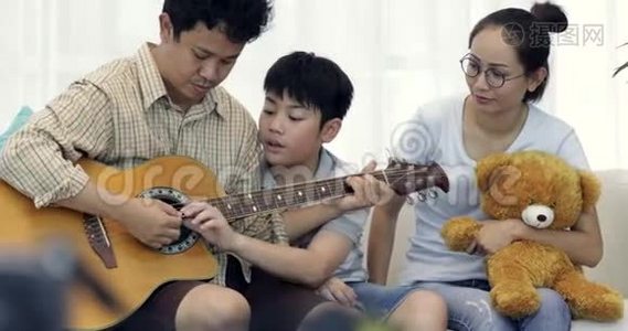 快乐的亚洲父亲在家为家人弹吉他视频