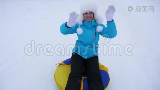 美丽的年轻女子在雪地里滑过充气的雪管和波浪手。 快乐的女孩滑过雪地视频