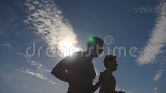 日落时分在乡下慢跑的男人剪影。 两名男子慢跑训练马拉松跑。 运动运动员视频
