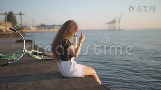 年轻的美女骑着自行车在日落或日出的时候在海边玩得很开心视频