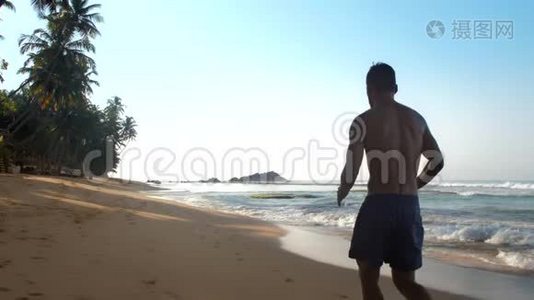 强壮的运动员沿着黄色沙滩慢跑视频