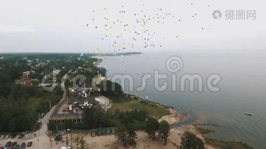 空中拍摄了许多五颜六色的气球飞上海面的天空视频
