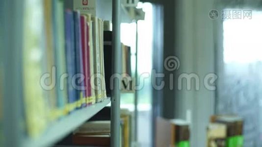 学生女孩在图书馆的书架中挑选视频