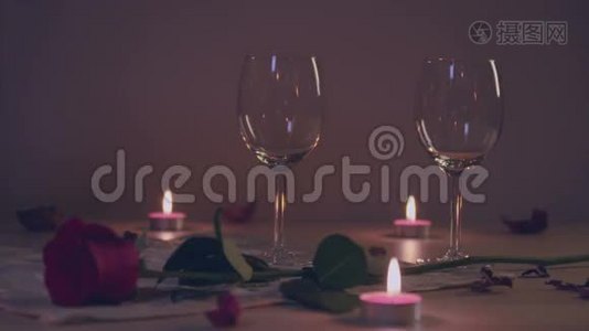 在酒杯里斟红酒，用玫瑰，蜡烛的浪漫场景.. 慢动作。视频