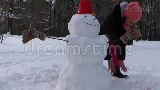 这个女孩在冬天的森林里堆雪人。视频