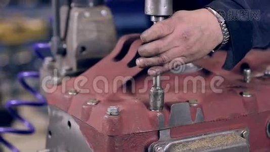 工人用自动螺丝刀拧紧发动机上的螺母。视频