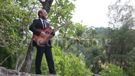 吉他手对热带树木的演奏和手势视频