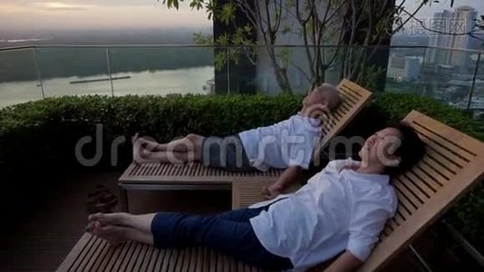 视频退休的亚洲夫妇坐在屋顶一起看日出。 抽象人生目标视频