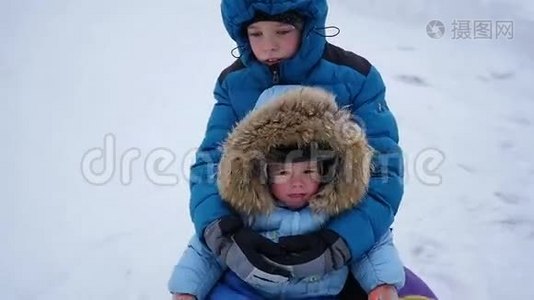 一个快乐的孩子骑着车，在雪山上的雪管里微笑视频