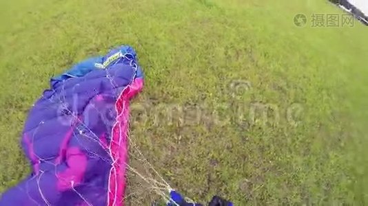 专业跳伞员在降落后在绿野上系降落伞。 极限运动。视频