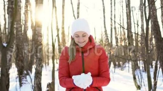 美丽的年轻女子在阳光明媚的冬季公园里，玩雪，玩得开心，微笑。 慢动作视频