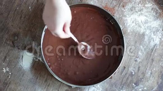 一个女人把巧克力面团倒在烤盘里，然后把它弄平视频