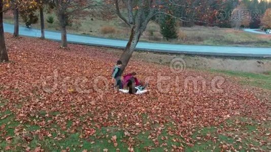 妈妈和她的孩子们在秋天的森林里玩得很开心。 他们跳起来把树叶扔到空中。 他们在笑。 这就是视频