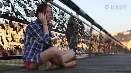 十几岁的女孩坐在恋人的桥上，用手机聊天。视频