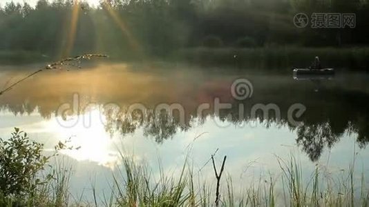 渔夫乘一艘充气船在河上漂浮。 太阳的光线在镜框里播放。 野外活动视频