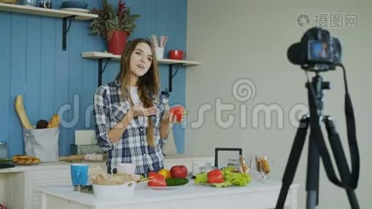 在厨房的dslr摄像头上，一位开朗、有魅力的视频博客上录制素食健康食品视频