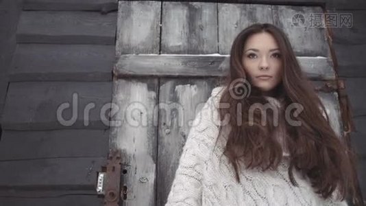 美丽的年轻女子穿着针织毛衣，在棚子边摆着工具。视频