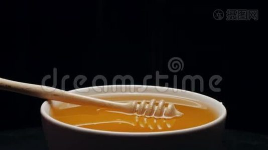 在黑色背景下分离的碗中加入蜂蜜的蜜盘视频
