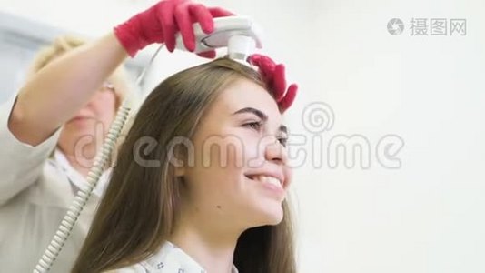 皮肤科医生诊断一个年轻漂亮女孩的头发结构与一个特殊的工具-一个旋毛镜。视频